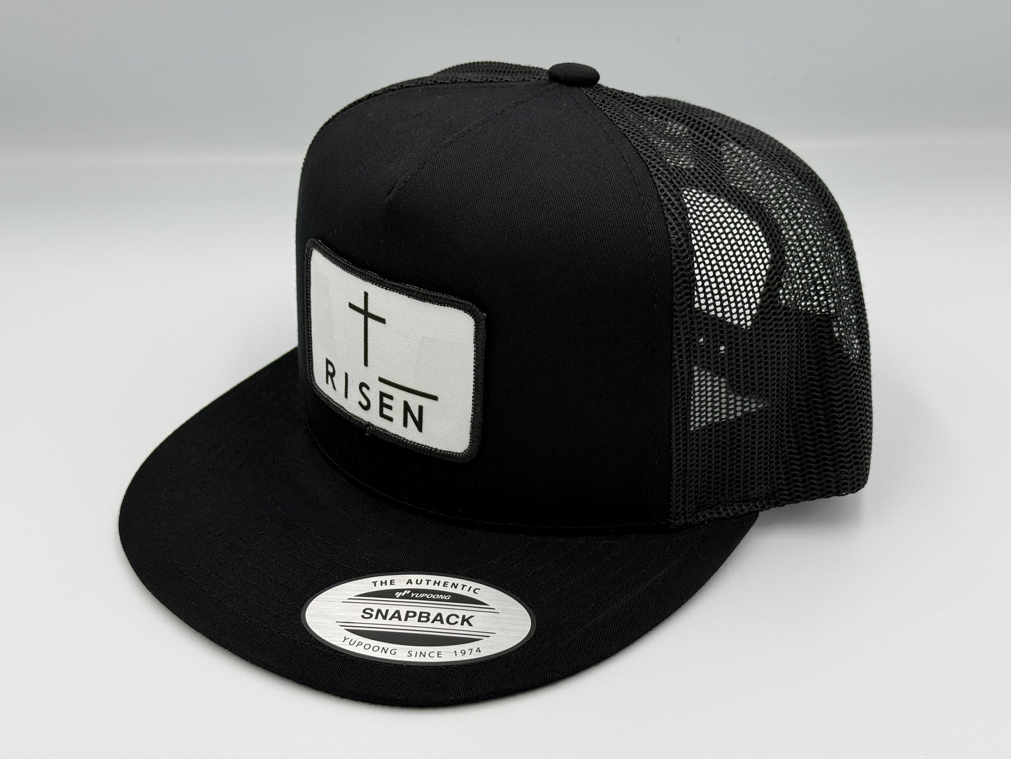Black Trucker Snapback Hat with RISEN canvas patch and mesh back for durability and style.